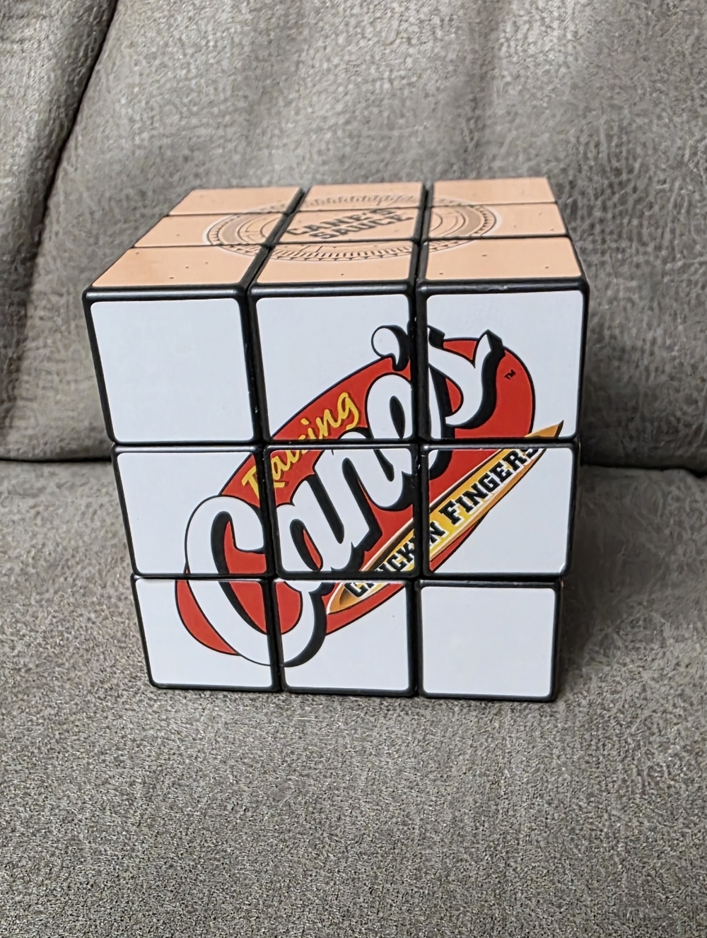 promotional 3x3 Rubik's Cube branded with the Raising Cane's logo